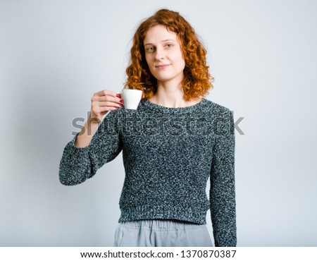beautiful curly woman with a cup of coffee isolated on gray background