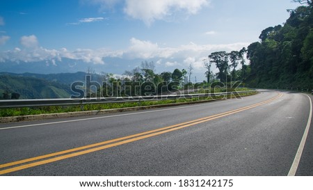 Beautiful curve asphalt road on the green mountain with more clouds on mountain and blue sky background , road in Northern of Thailand
