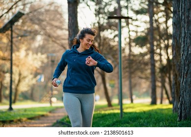 A Beautiful Curvy Woman Runs In A Nature Park At Sunset.