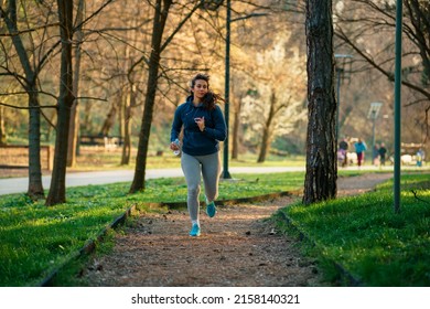 A Beautiful Curvy Woman Runs In A Nature Park At Sunset.