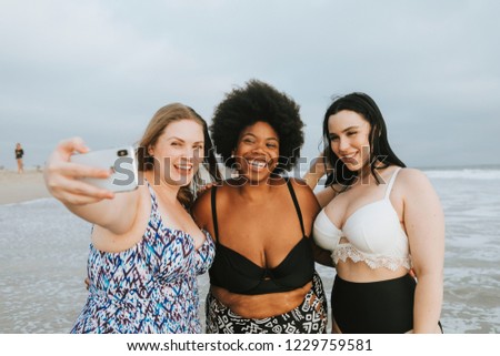 Beautiful curvy women taking a selfie at the beach