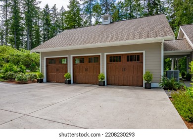 Beautiful custom built craftsman style home three car garage with wooden doors lush landscaping with spring foliage and shadows dappling the yard