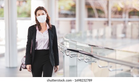 Beautiful cute Asian businesswoman wearing protective surgical hygiene mask on face in the situation of coronavirus outbreak, walking to office in city. Idea for preventing, protect health from virus. - Powered by Shutterstock