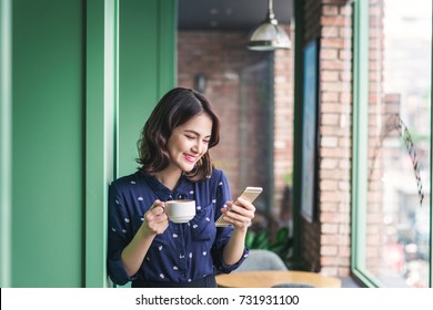 Beautiful cute asian young businesswoman in the cafe, using mobile phone and drinking coffee smiling - Powered by Shutterstock