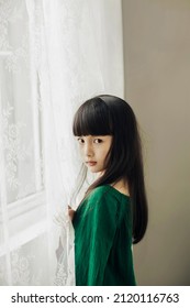 Beautiful Cute Little Asian Girl On The Edge Of The White Window Screen