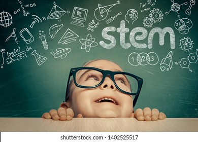 Beautiful Cute Little Girl With Eyeglasses Looking At Colorful STEM Word And Symbols Above Her Head.  E-learning, Modern And Innovative Stem Education Concept.