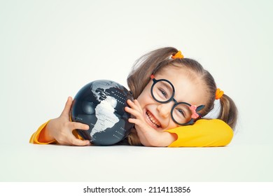 Beautiful Cute Little Girl With Glasses Holding Globe And Smiling To The Camera. Smart Student Studying Geography With Earth.  Little Clever Genius Portrait. Save The World Concept.