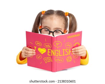 Beautiful cute little girl with glasses reading English grammar book in front of white background. Foreign language learning and speaking concept. I love English. Back to school.