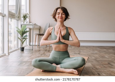 Beautiful cute sporty woman doing exercise in bright room. Focused on brunette sitting on the floor practicing yoga wear tip and leggings. Home mood, lifestyle 