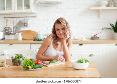 Beautiful cute young smiling woman on the kitchen is preparing a vegan salad in casual clothes. Diet and dieting concept - Powered by Shutterstock