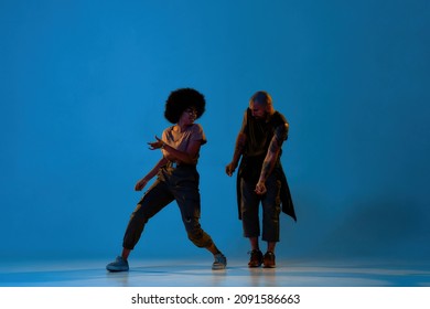 Beautiful Dance Couple Dancing Hip Hop Dance. Concept Of Contemporary Dancing. Idea Of Choreography. Young Caucasian Man And Black Girl On Blue Background In Studio With Shadow On Floor. Copy Space