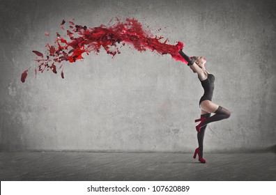 Beautiful dancer with a wake of red paint coming out from her hands