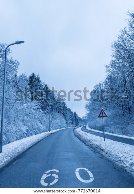 Beautiful and\
dangerous driving road in winter snow with 60 sign during cold\
weather at early december\
Netherlands