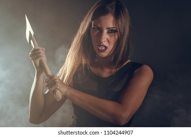 Beautiful dangerous girl with rusty axe want to revenge for violence she experience. Looking at camera.