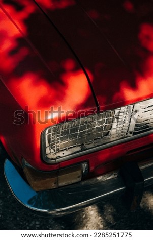 Beautiful dappled lighting on a crimson red car bonnet