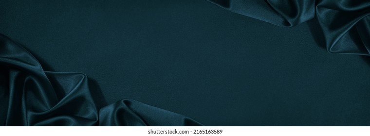 Beautiful dark blue green silk satin background. Soft folds on shiny fabric. Luxury background with copy space for design. Web banner. Wide. Flat lay, top view table. Christmas, Valentine.