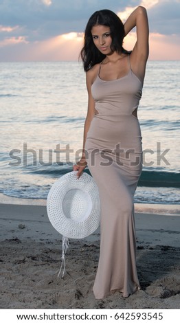 Beautiful dark haired woman in a brown dress on the beach.