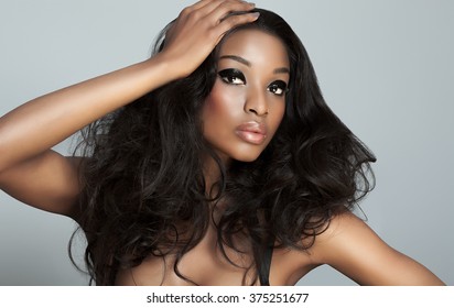 Beautiful dark model with big hair over gray background. Fashion and beauty with African dark skin model.