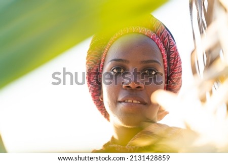 Beautiful dark skin young woman between palm branches on beach photo