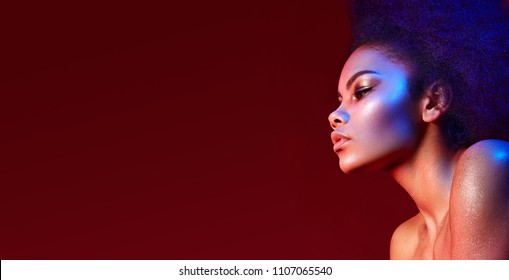 Beautiful dark-haired girl in profile on a claret background. Bright makeup and curvy hair in the style of "Afro". Color filters.fashion, beauty, makeup, cosmetics, beauty salon, style.