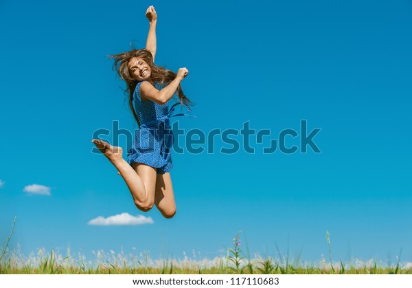 夏の青い空の背景に 美しい黒髪の幸せな若い女性が空高く飛び上がる の写真素材 今すぐ編集