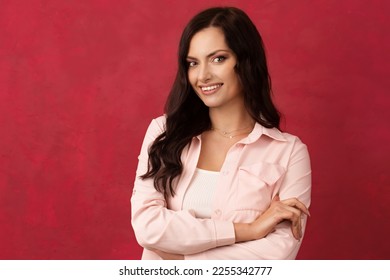 Beautiful dark-haired woman in a pink shirt on a pink background. Color of background Viva Magenta 18-1750, in 2023 - Shutterstock ID 2255342777
