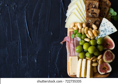 Beautiful Date Night Cheese Board with Sharp Cheddar Manchego and Blue Cheese Figs Crackers Green Olives and Prosciutto on Dark Background Copy Space - Powered by Shutterstock