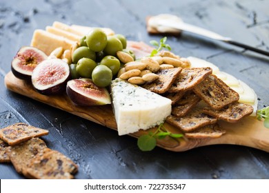 Beautiful Date Night Cheese Board with Sharp Cheddar Manchego and Blue Cheese Figs Crackers Green Olives and Prosciutto on Dark Background with Knife  - Powered by Shutterstock