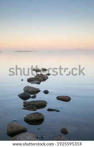 Beautiful dawn seascape with the steaming seawater and stepping stone rocks in the front