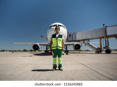 Beautiful Day At Airdrome. Full Length Portrait Of Airport Worker Standing On Runway Near Passenger Plane