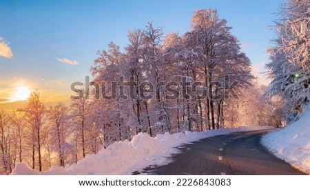 Beautiful day for drive through hilly landscape covered with freshly fallen snow. Wonderful winter day after snowstorm. Fairy-tale forest and valley views while driving along winding mountain road.