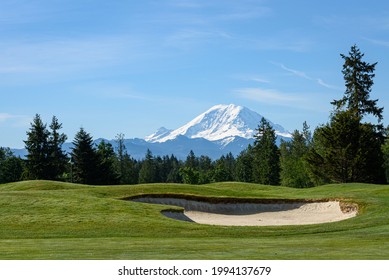 Beautiful day on a golf course, green fairway and bright sand trap with Mt Rainier in the background
				