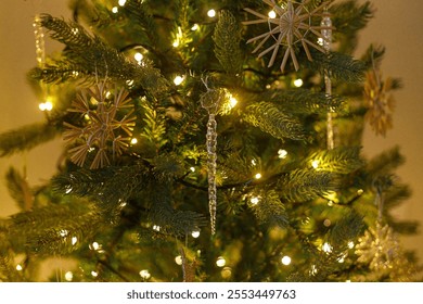 Beautiful decorated christmas tree with straw snowflake, vintage baubles and golden lights. Winter holidays preparation. Atmospheric magical eve. Stylish christmas ornament on tree close up