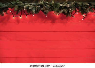 Beautiful decorated christmas wooden background with garland,tree branch on top.Merry Christmas & Happy New Year wallpaper.Place text on red wooden xmas backdrop