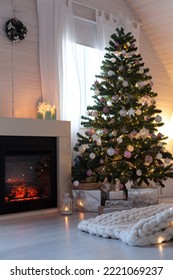 Beautiful Decorated Evergreen Glowing Fir Tree With Pastel Color Balls And Garland Lights Near Fireplace. Christmas Cozy Scandic Decoration At Wooden House. New Year Hygge Cabin Interior, No People. 