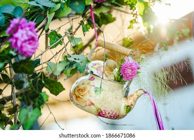 Beautiful decoration made of porcelain tea pot and fresh flowers. Outdoor event or wedding decoration