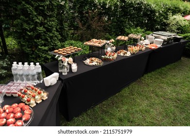 A beautiful decoration of the wedding buffet table outdoors with sweets, fresh flowers on wooden coasters,an abundance of sweets on wooden coasters.,buffet reception in nature.