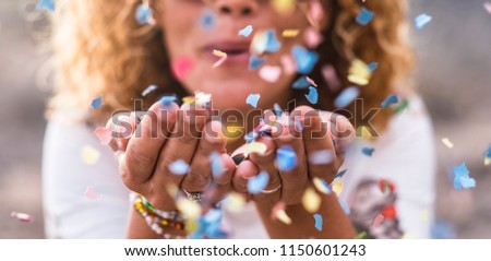 beautiful defocused woman blow confetti from hands. celebration and event concept. happiness and coloured image. movement and happiness having fun