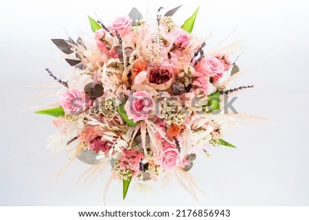 a beautiful delicate bouquet of stabilized flowers, roses, dried flowers, twigs of leaves on a light background is isolated, close ,selective focus. bridal bouquet, gift bouquet