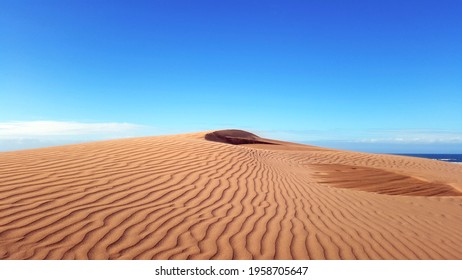 beautiful desert red sand dune with blue sky in the background. wind waves effects or ripples lines on sands close up. - Shutterstock ID 1958705647