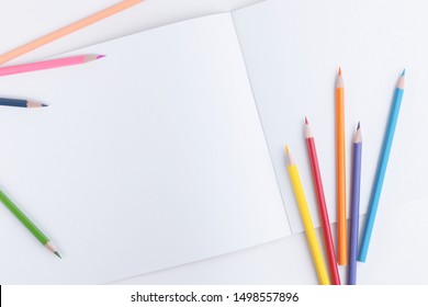 Beautiful designer composition with a group of scattered colored wooden pencils and an open sketchbook with empty pages for text, picture or other design element - Powered by Shutterstock