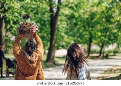 Beautiful Diverse Family Having Fun While Spending Their Free Time In The Park. Happy Multiracial Mother, Father And Daughter Enjoying A Day In The Park. Father Holding His Baby Girl.