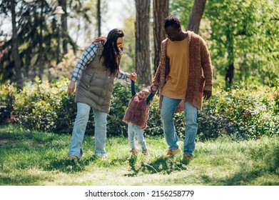 Beautiful Diverse Family Having Fun While Spending Their Free Time In The Park. Happy Multiracial Mother, Father And Daughter Enjoying A Day In The Park.