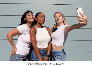 Beautiful diverse women taking a selfie, wearing plain white clothes, group of young diverse woman taking selfie wearing white plain clothes, young woman wearing white clothes taking selfie - Powered by Shutterstock