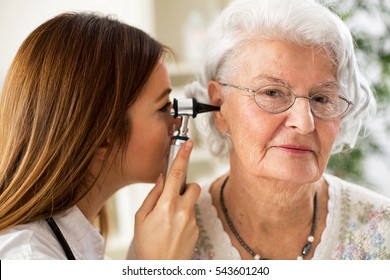 Beautiful doctor holding otoscope and examining patient ear - Powered by Shutterstock