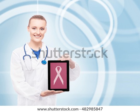 Beautiful doctor with tablet and pink ribbon on it on blink background. Breast cancer concept.