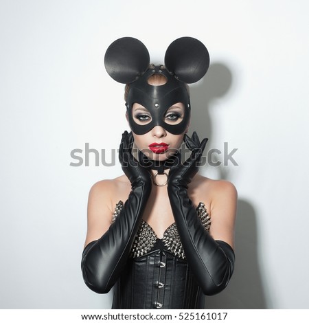 Beautiful dominant blonde vamp mistress girl in leather corset, gloves, collar and bdsm black leather fetish cat mask posing on white backgroung