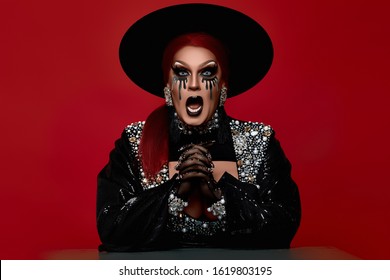 Beautiful Drag Queen In A Black Hat Rhinestones On A Red Background