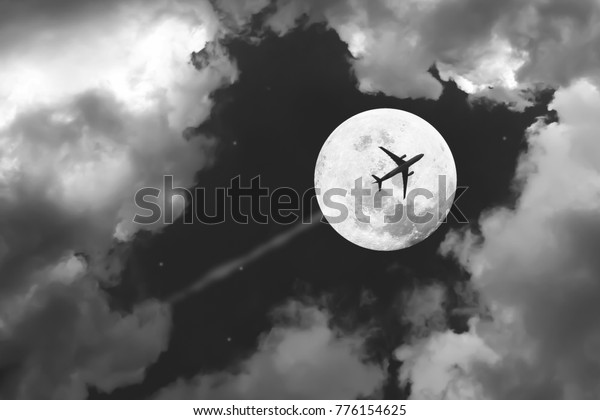 Beautiful dramatic atmosphere of\
airplane in black and white night sky with jet and full moon\
night.