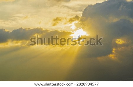 Beautiful dramatic crepuscular rays shining through clouds, divine god rays sunbeams in golden sunset sky, nature background
